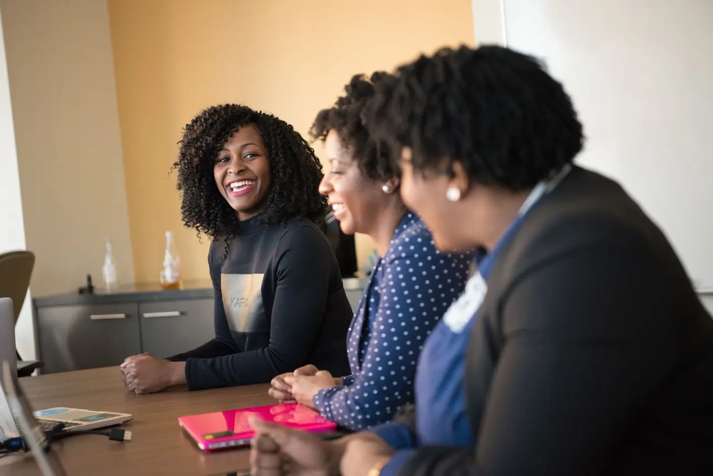 Trois femmes qui échangent en souriant autour d'une table