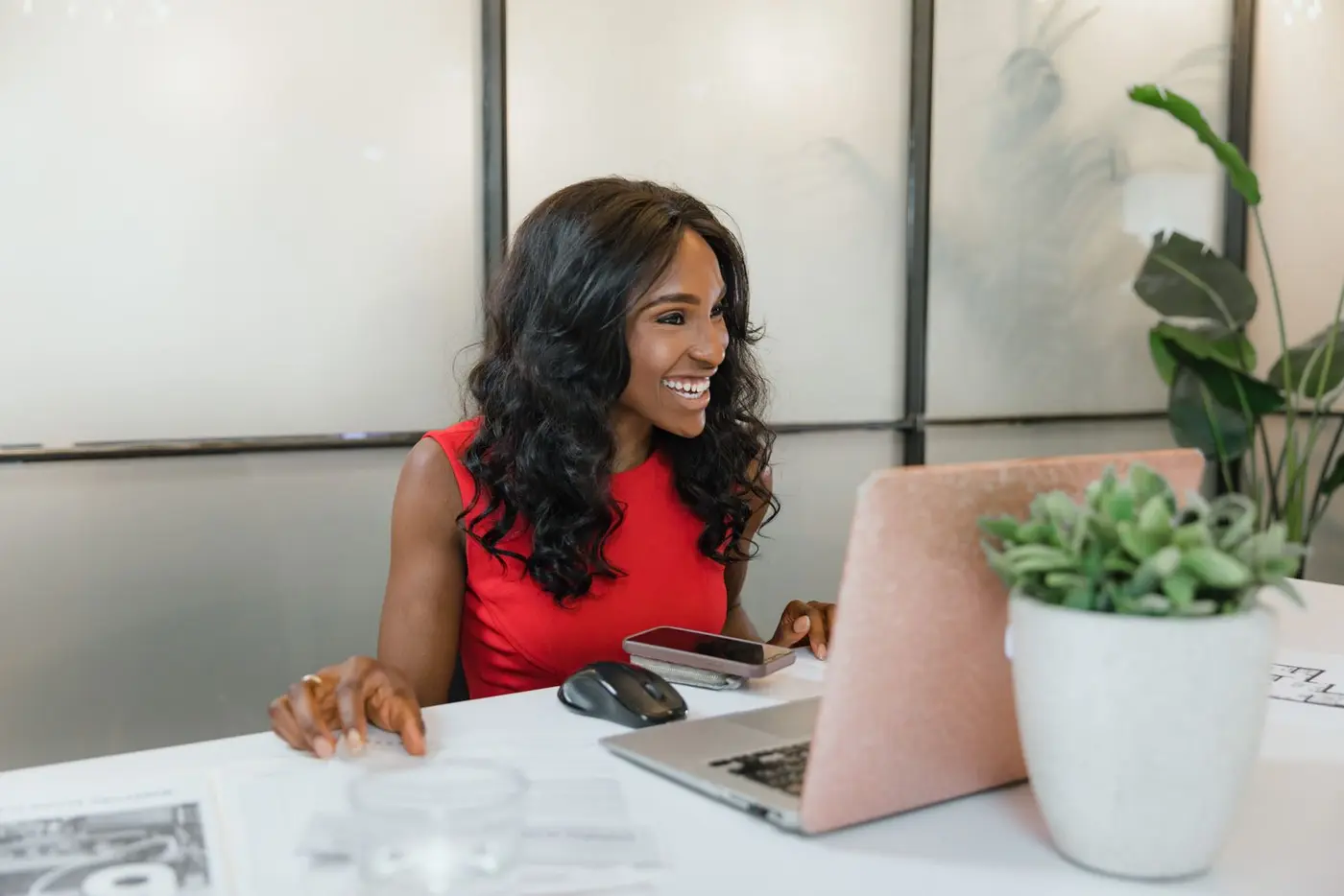 Femme souriante qui travaille sur son ordinateur et son téléphone